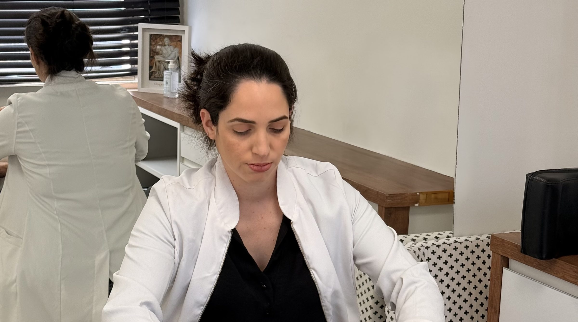 Paula com as mãos na cervical de um paciente deitado na maca